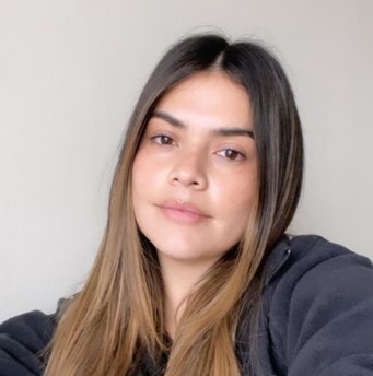 Close-up portrait of a young woman with long brown hair, looking at the camera.